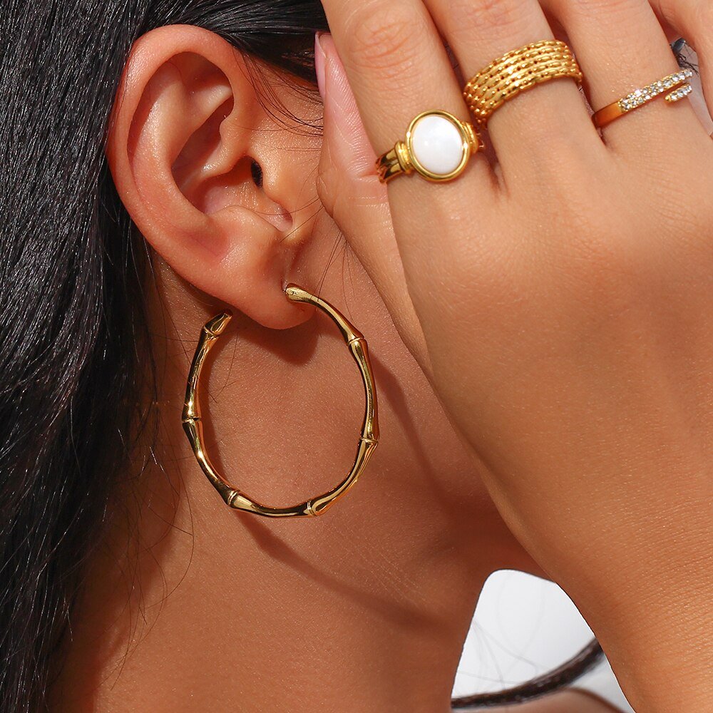 A woman wearing the Large Gold Bamboo Hoops.