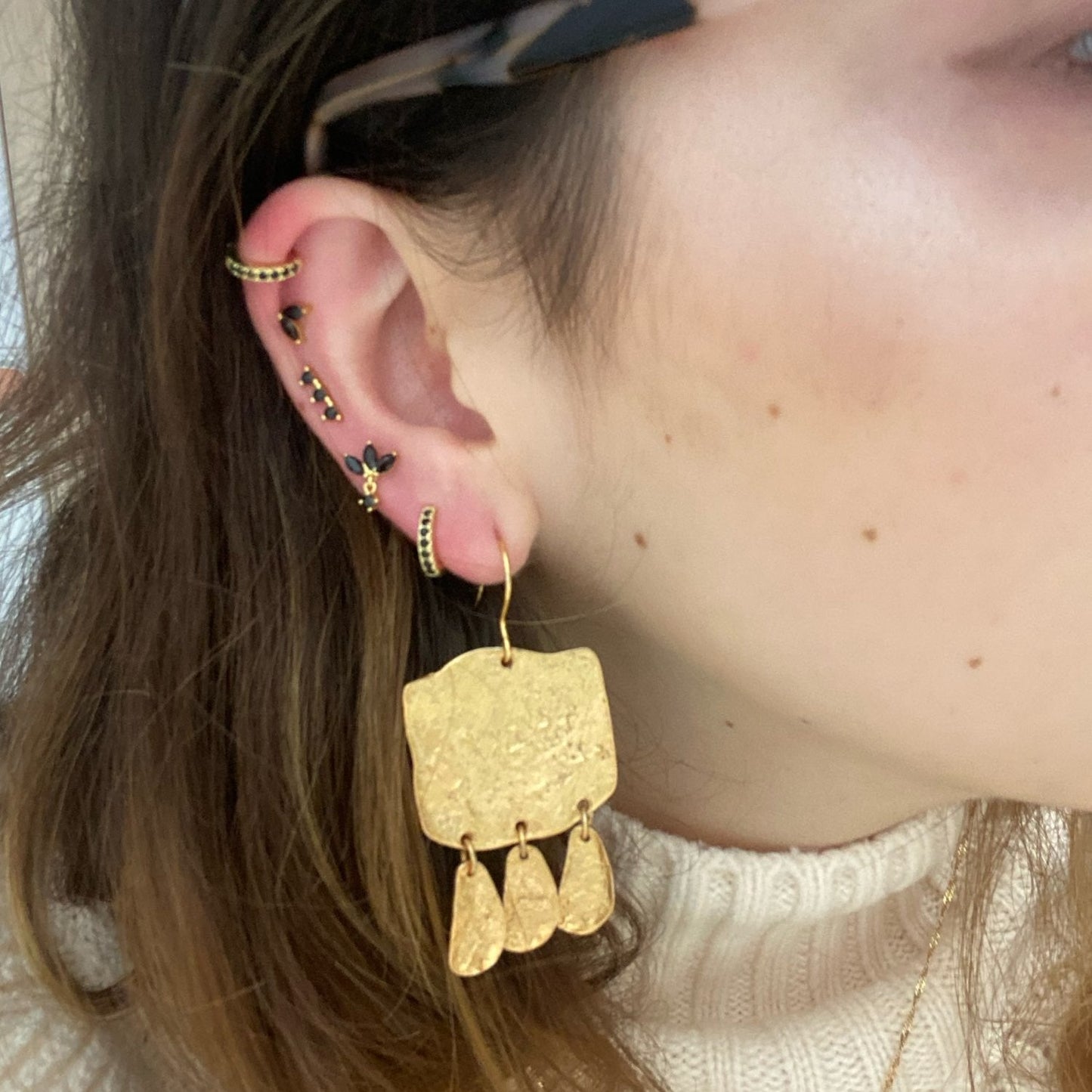 A woman wearing multiple gold ear piercings.