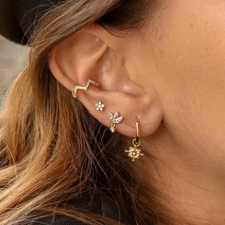 A model wearing multiple gold CZ stud earrings.