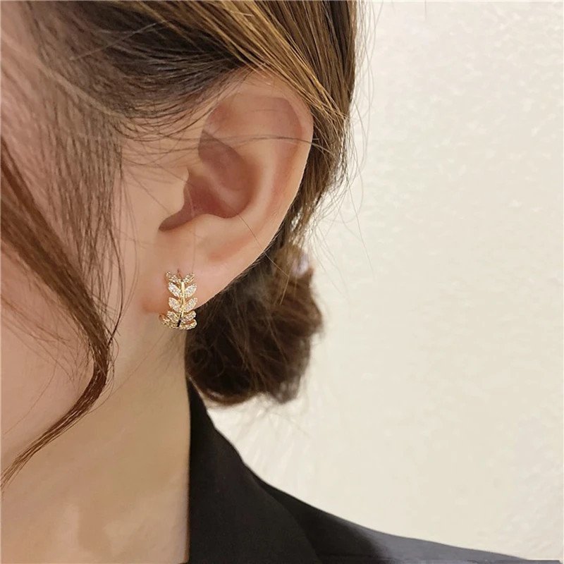 A woman wearing CZ laurel leaf hoop earrings.