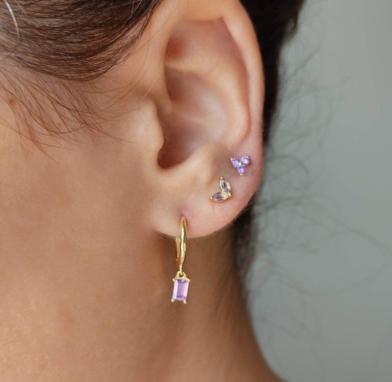 A model wearing the Lilac Trinity Studs in Gold with Lilac Marquise Studs.