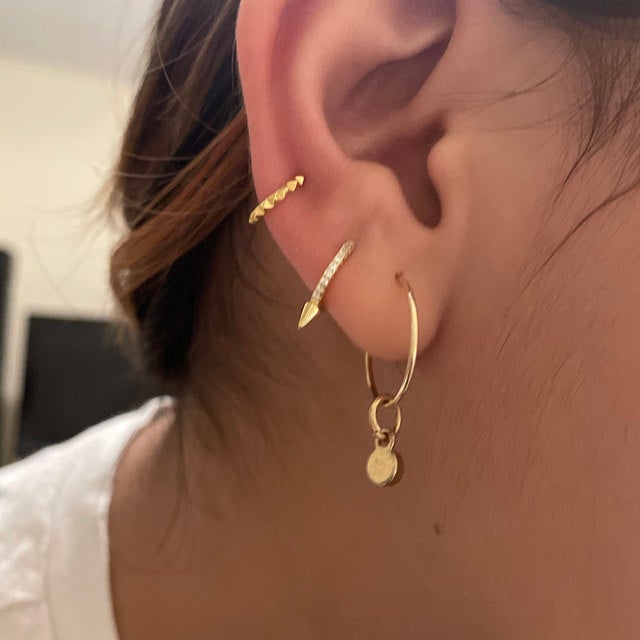 A woman wearing multipe gold mini hoops.