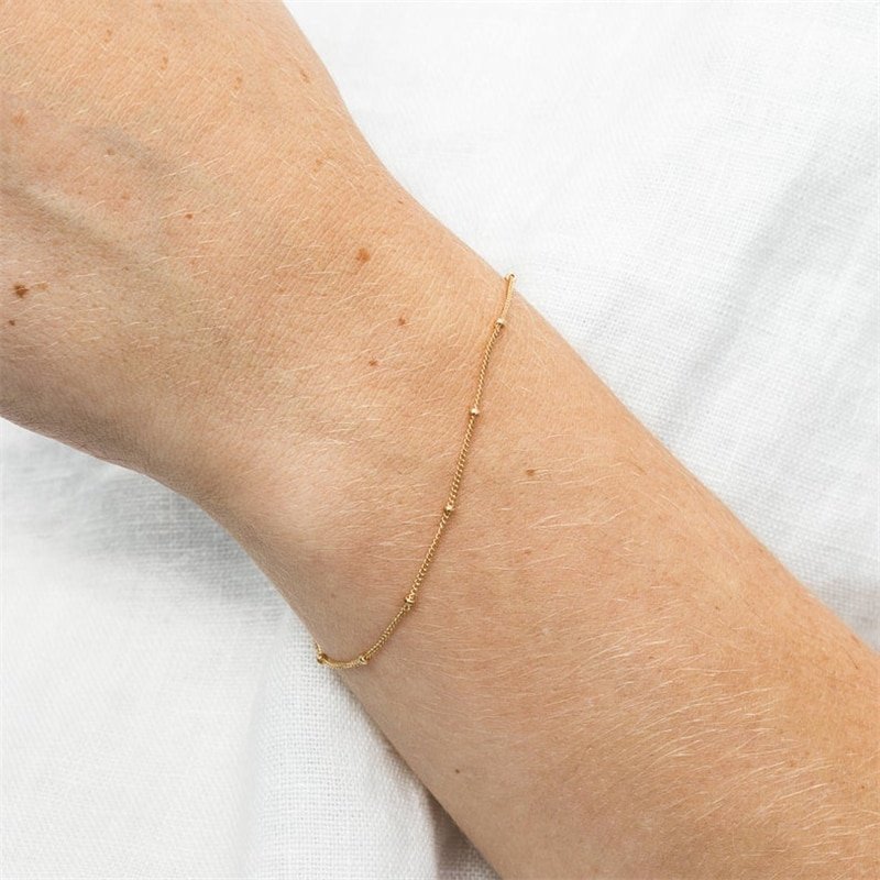 A model wearing a minimal delicate chain bracelet.