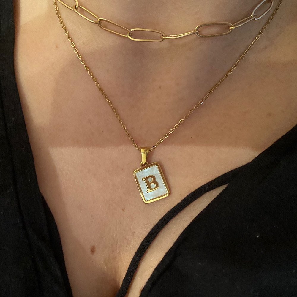 A model wearing a B initial mother of pearl gold necklace.