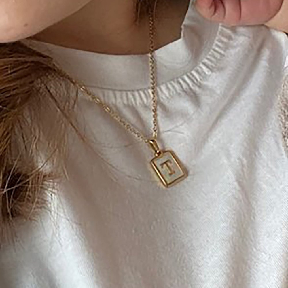 A model wearing a Gold Mother of Pearl Monogram Necklace, Letter T.