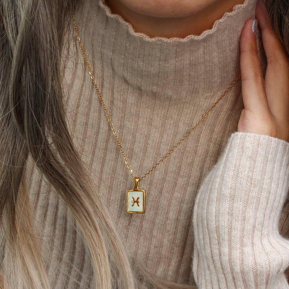 A model wearing a gold zodiac pendant necklace.