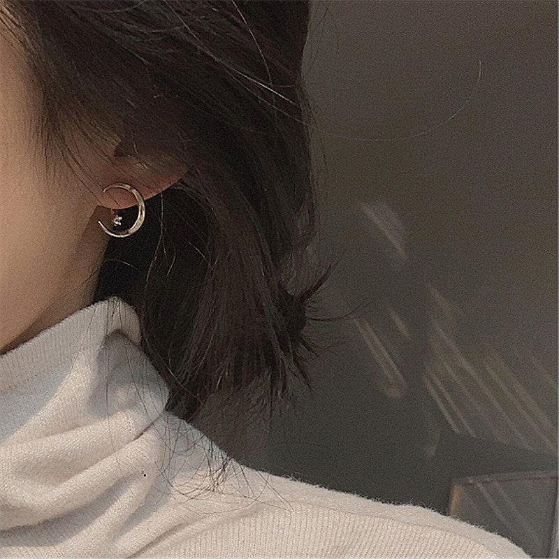 A woman wearing crescent moon ear jacket earrings.