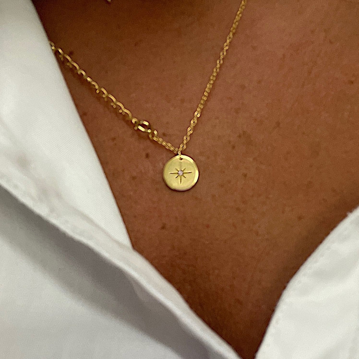 A woman wearing a coin pendant necklace with a star motif.