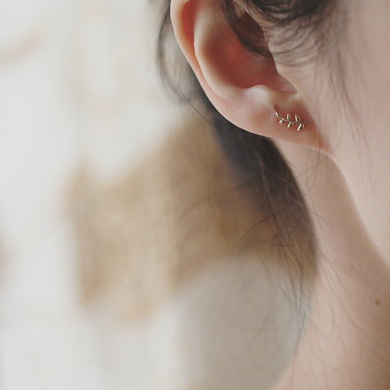 A model wearing tiny Olive Branch Studs.