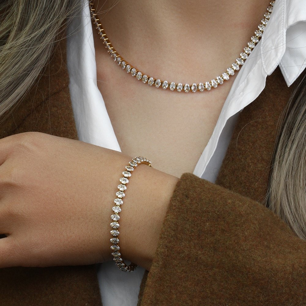 A woman wearing the Oval CZ Gold Tennis Bracelet and Necklace.