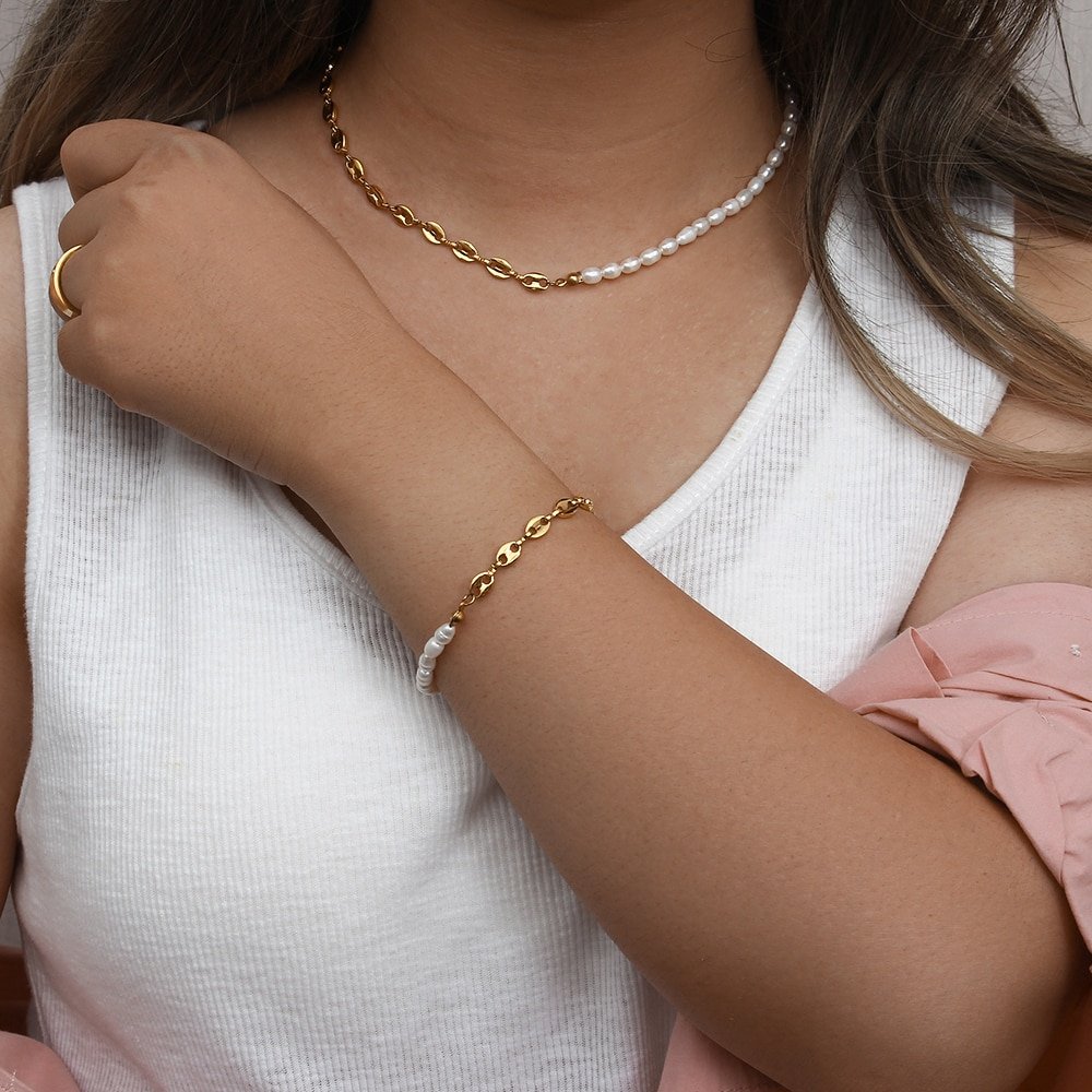 A model wearing a matching gold pearl bracelet and necklace set.