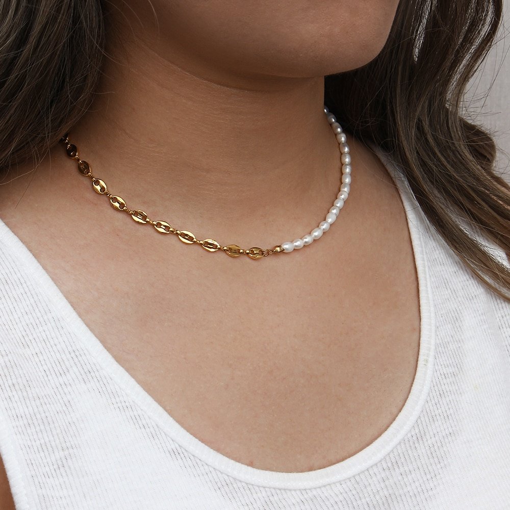 A model wearing a split gold chain and pearl necklace.