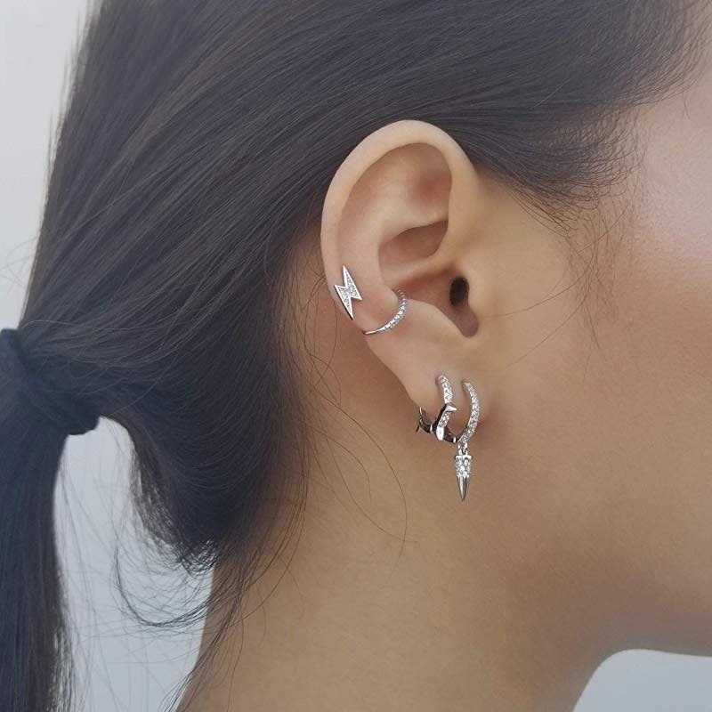 A model wearing silver spike huggie earrings.