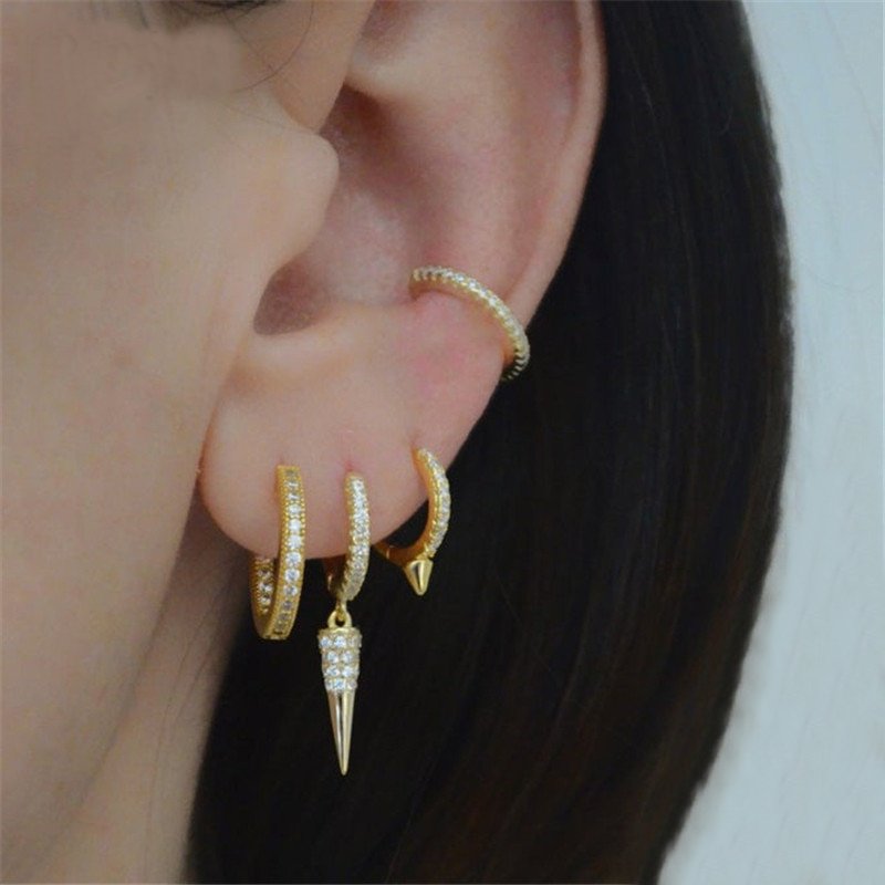 A model wearing gold huggie earrings with CZ stones.