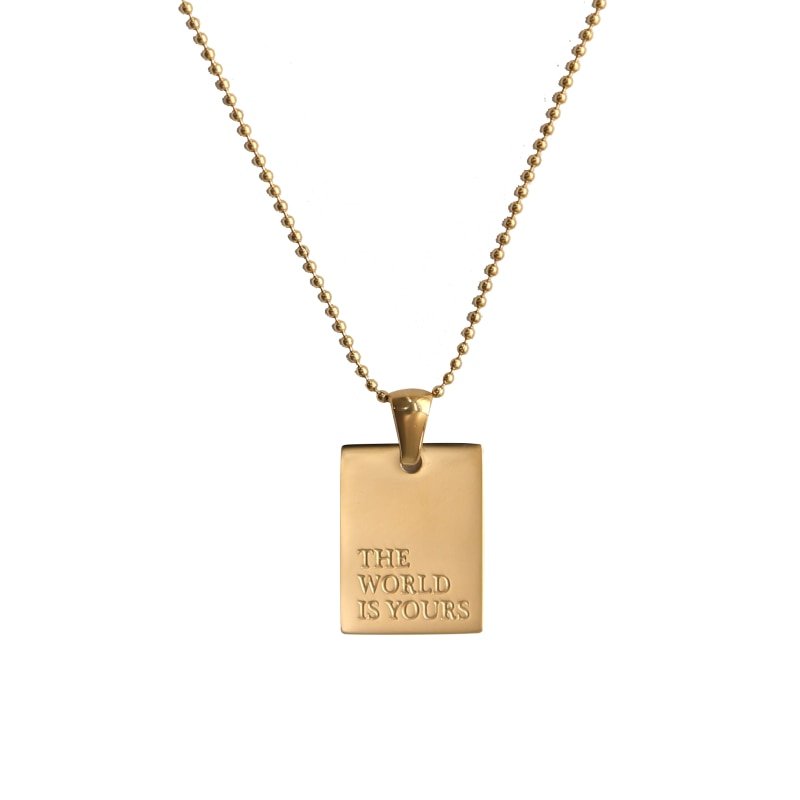 Gold dog tag necklace with "The World Is Yours" engraved.