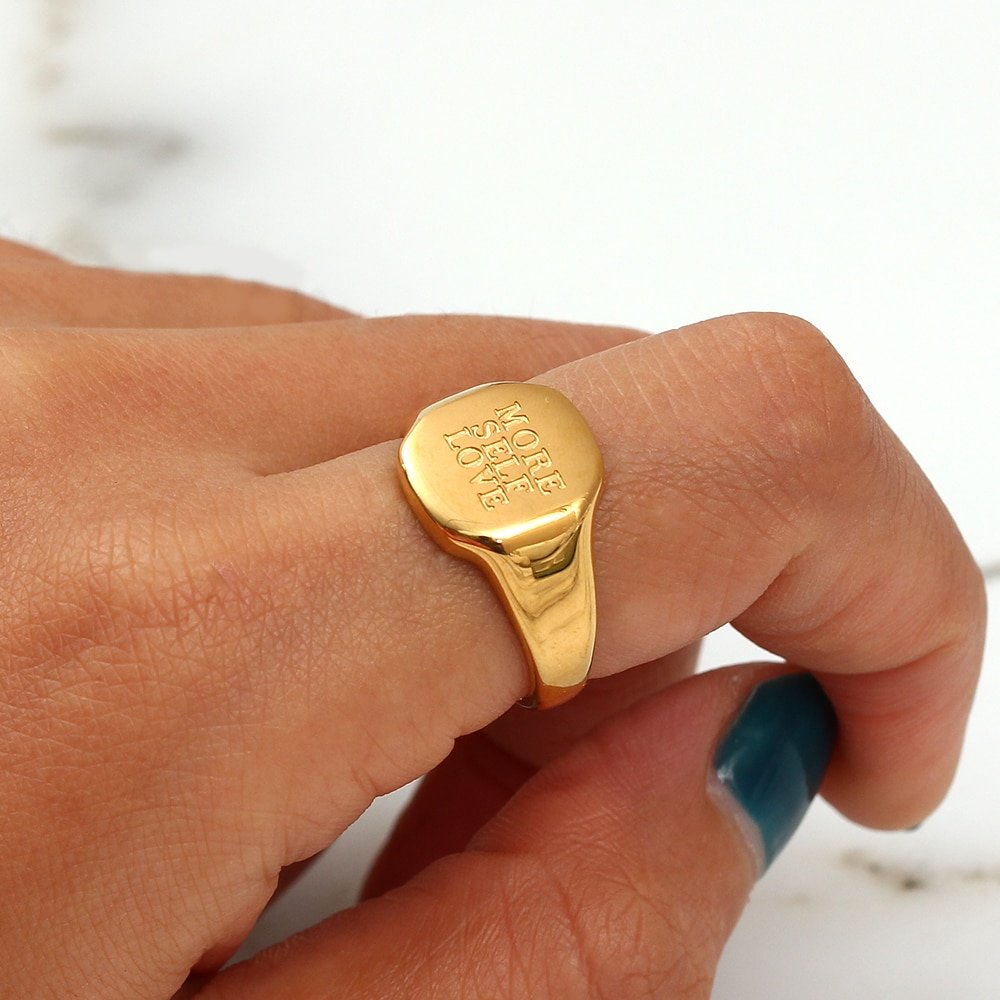 A model wearing a gold signet ring with "More Self Love" engraved.