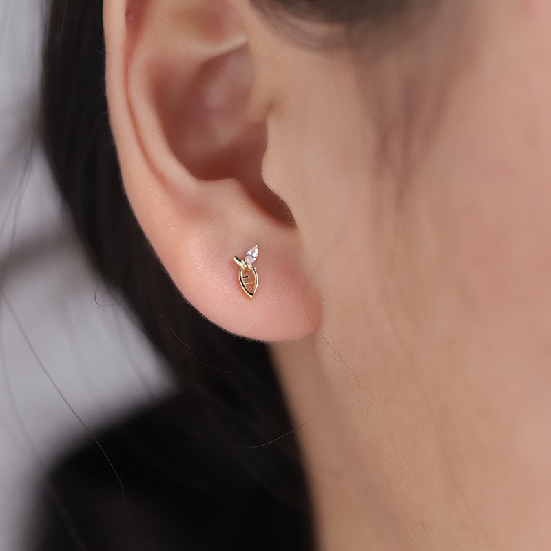 A model wearing tiny gold carrot stud earrings.