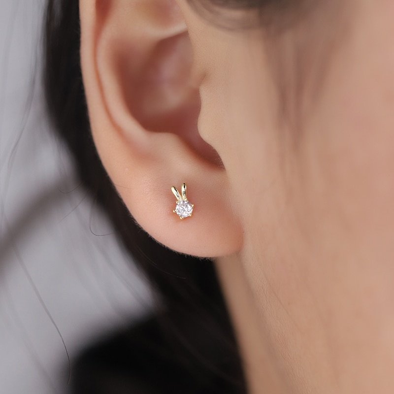 A model wearing a tiny gold and CZ rabbit stud earring.