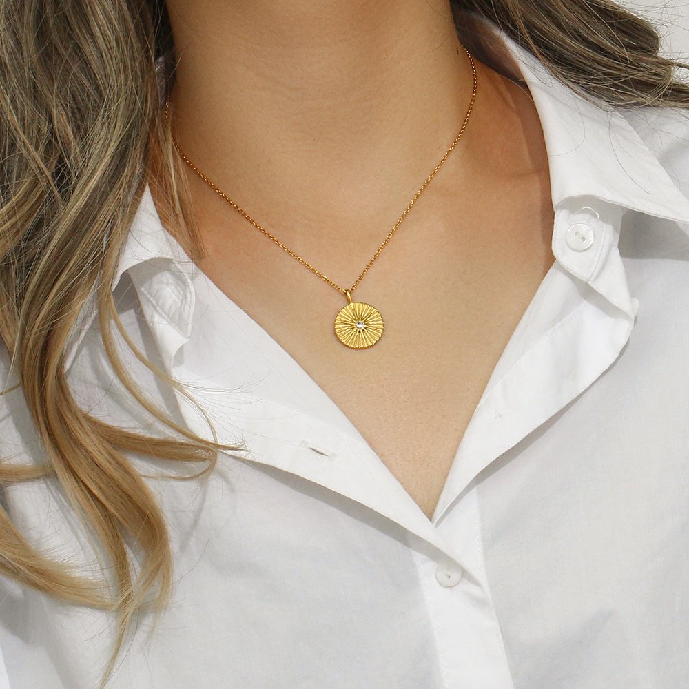 A woman wearing a gold coin necklace with a star.