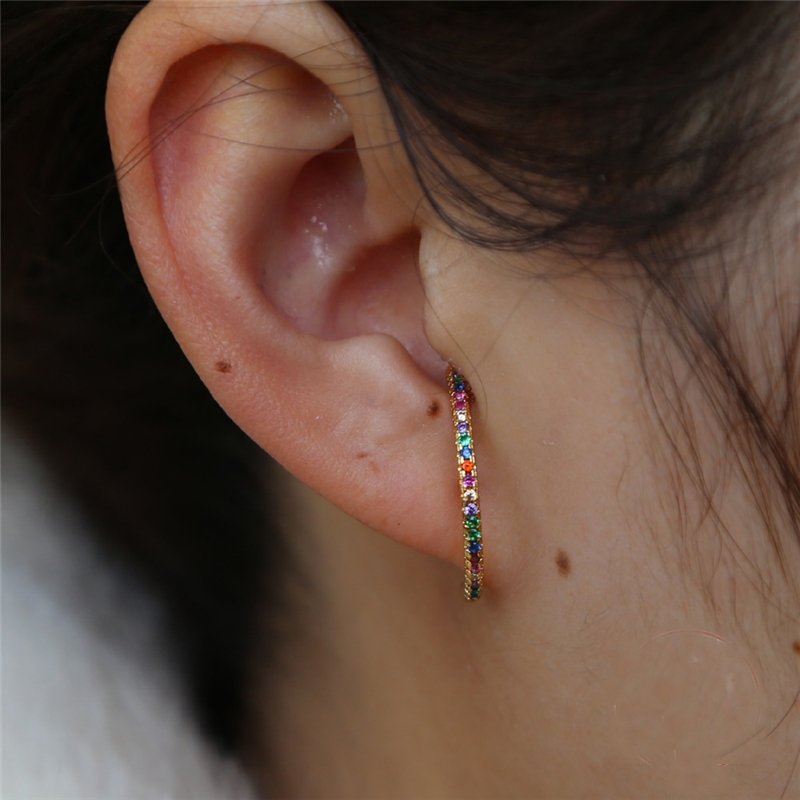A woman wearing a suspender earrings with colorful CZ stones.