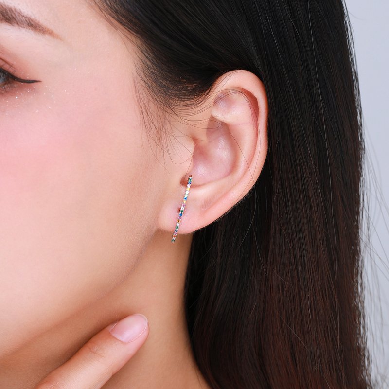 A woman wearing a bar stud with multi colored stones.