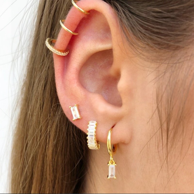 A model wearing multiple gold piercings with clear CZ stones.