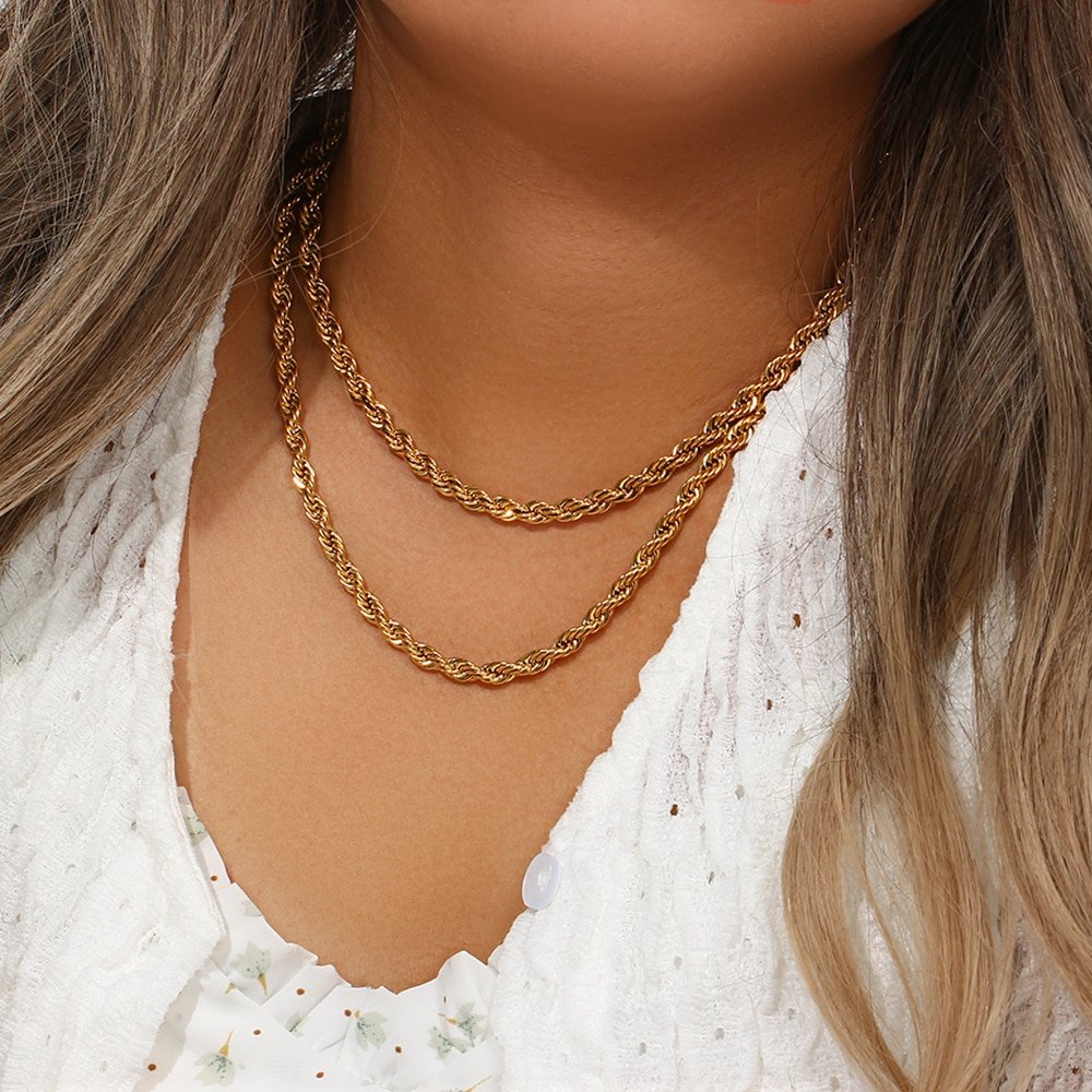 A woman wearing two gold rope chain necklace.