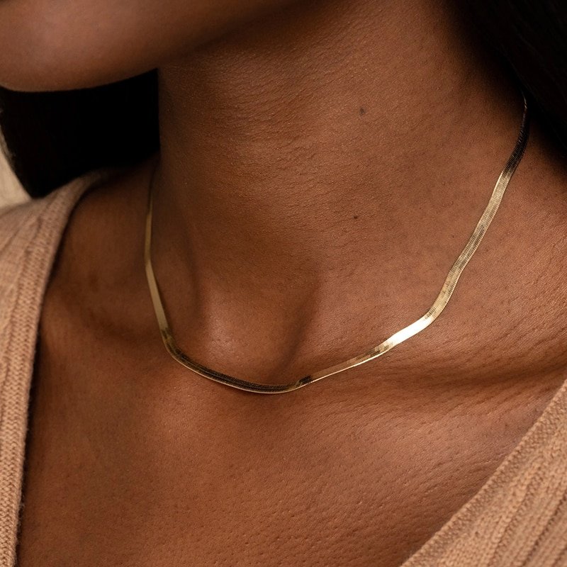 A model wearing a short gold herringbone necklace.