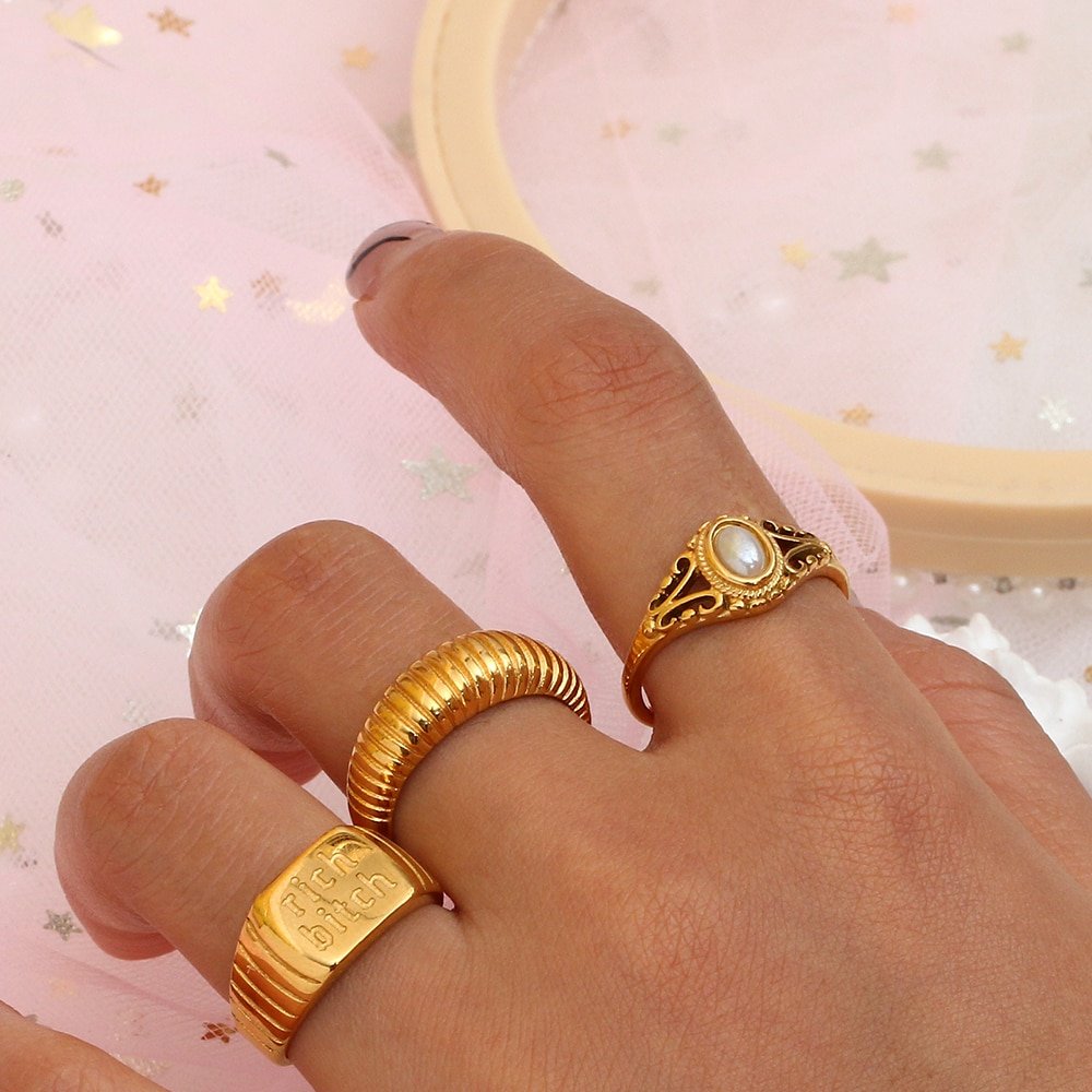 A woman wearing multiple gold statement rings.