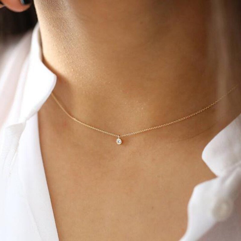 A model wearing a short dainty gold chain necklace with a single CZ pendant.