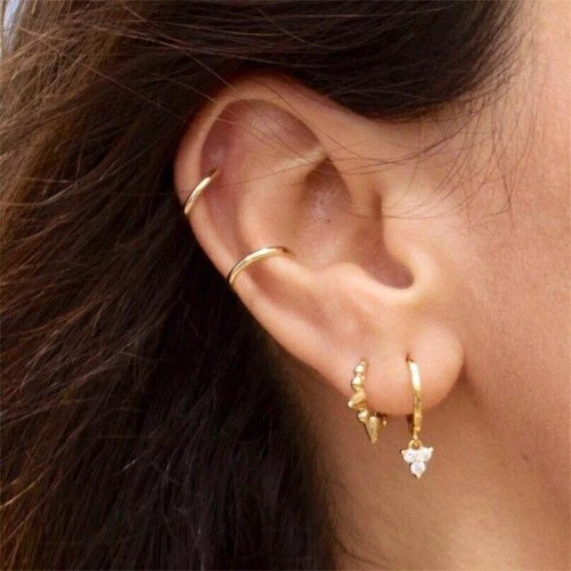 A model wearing multiple gold ear cuff earrings.