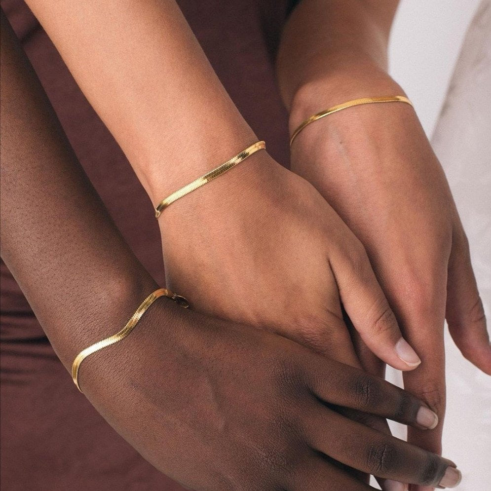 Gold chain bracelet on three different skin tones.