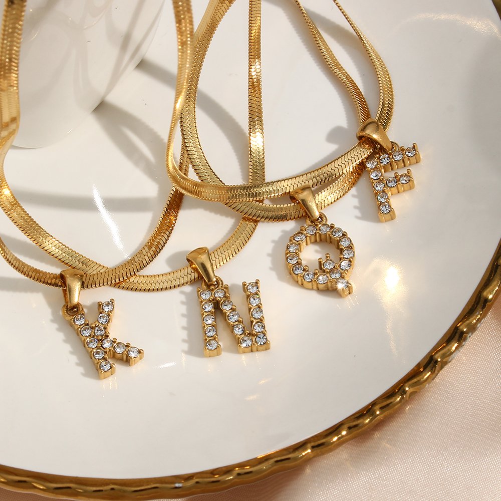 Closeup of multiple gold initial necklaces.