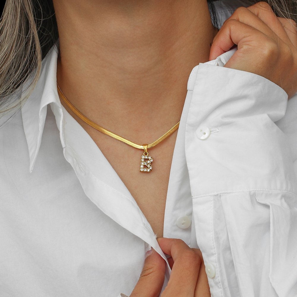 A model wearing a gold initial necklace.