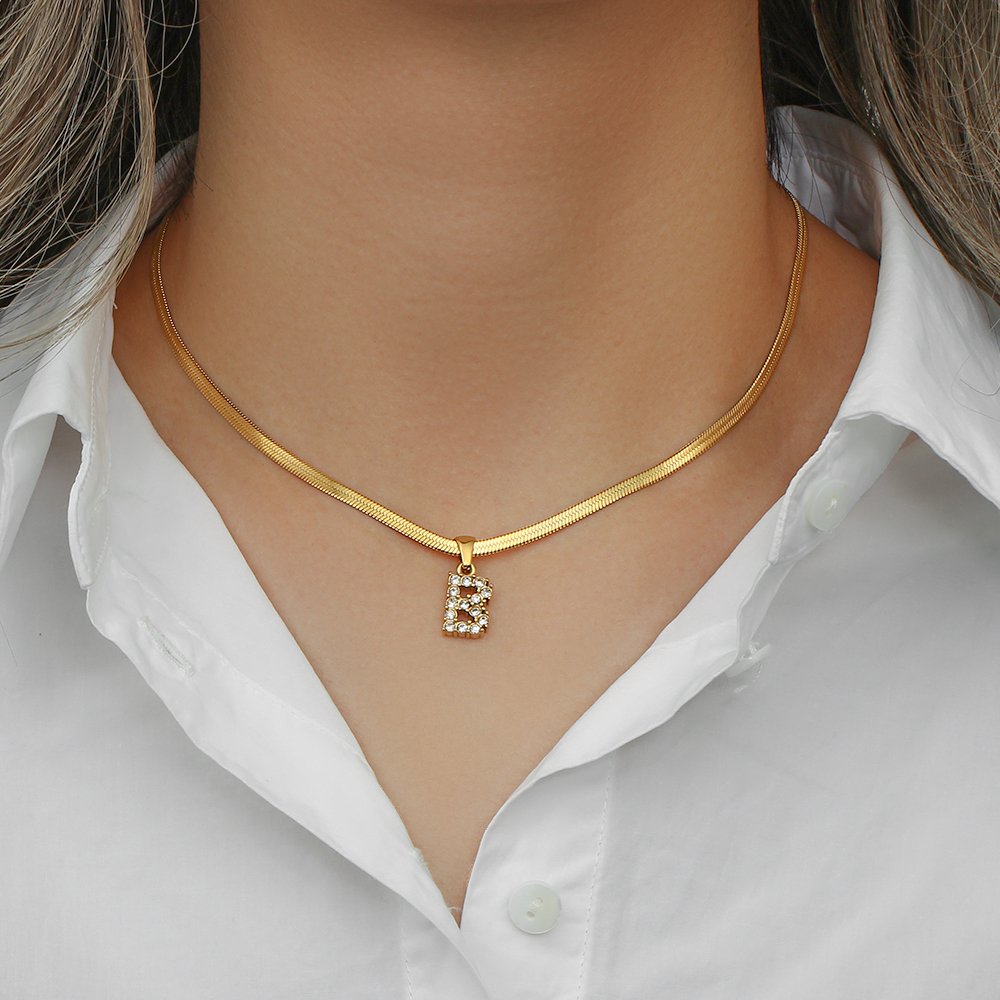 A woman wearing a CZ pave initial necklace.