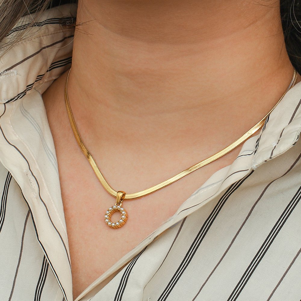 A woman wearing a gold initial necklace.
