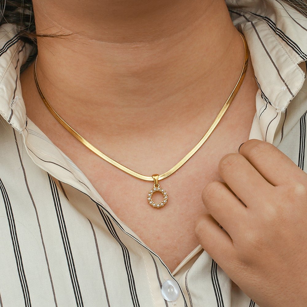 A model wearing a gold initial pearl necklace.