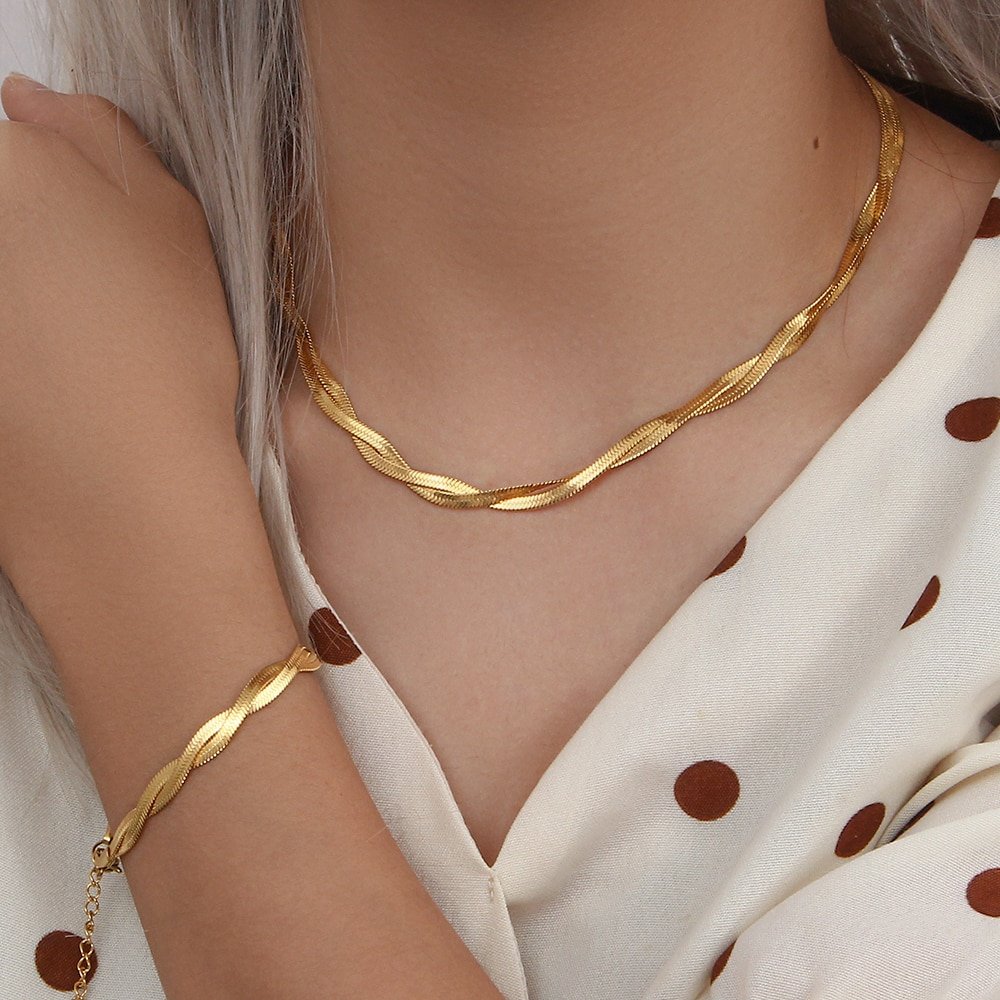 A model wearing a gold snake chain bracelet and necklace set.