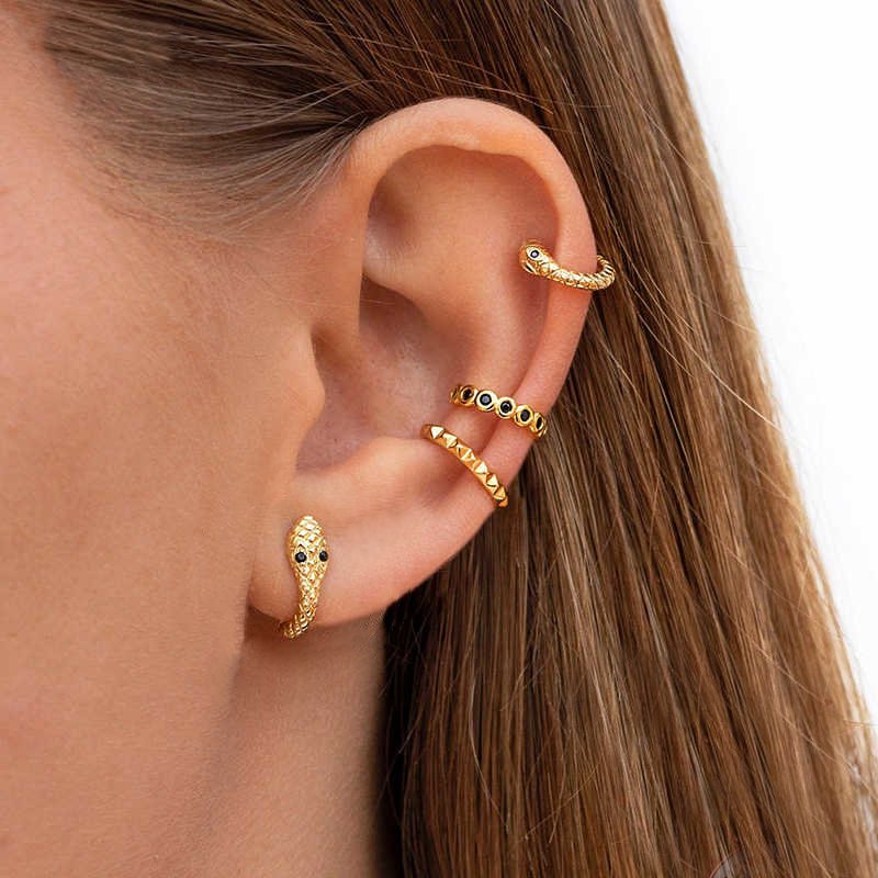 A model wearing gold snake huggie earrings.