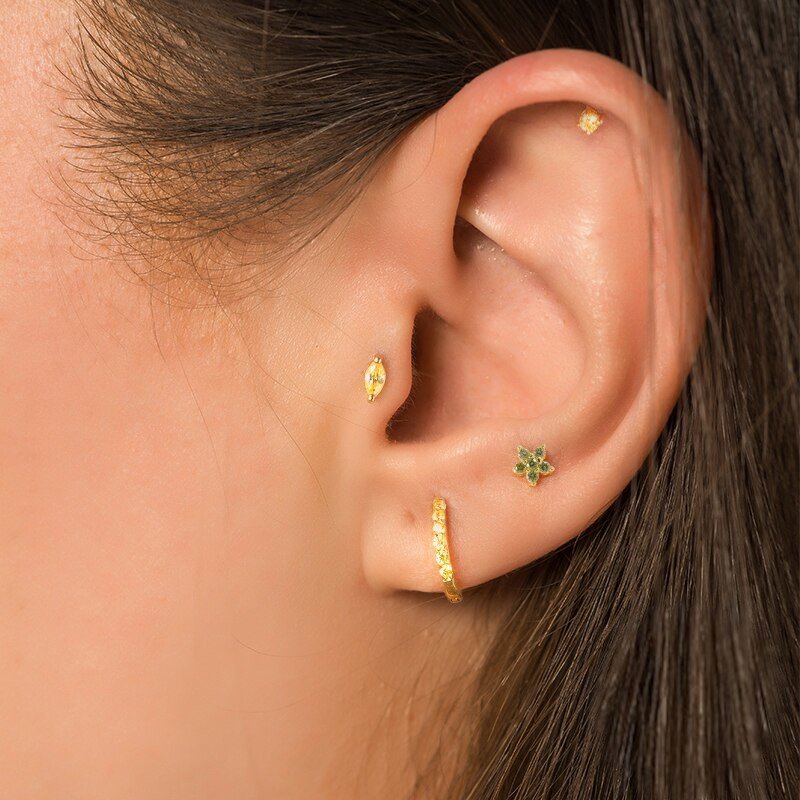 A model wearing gold earrings with green stones.