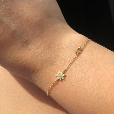 A woman wearing a delicate chain bracelet with star charm.