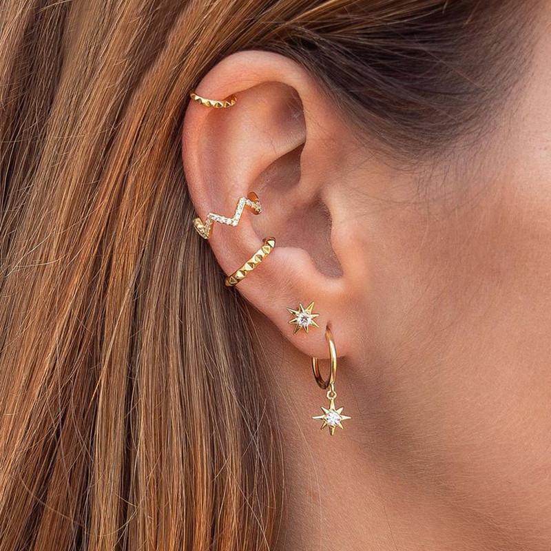 A model wearing multiple gold star earrings.