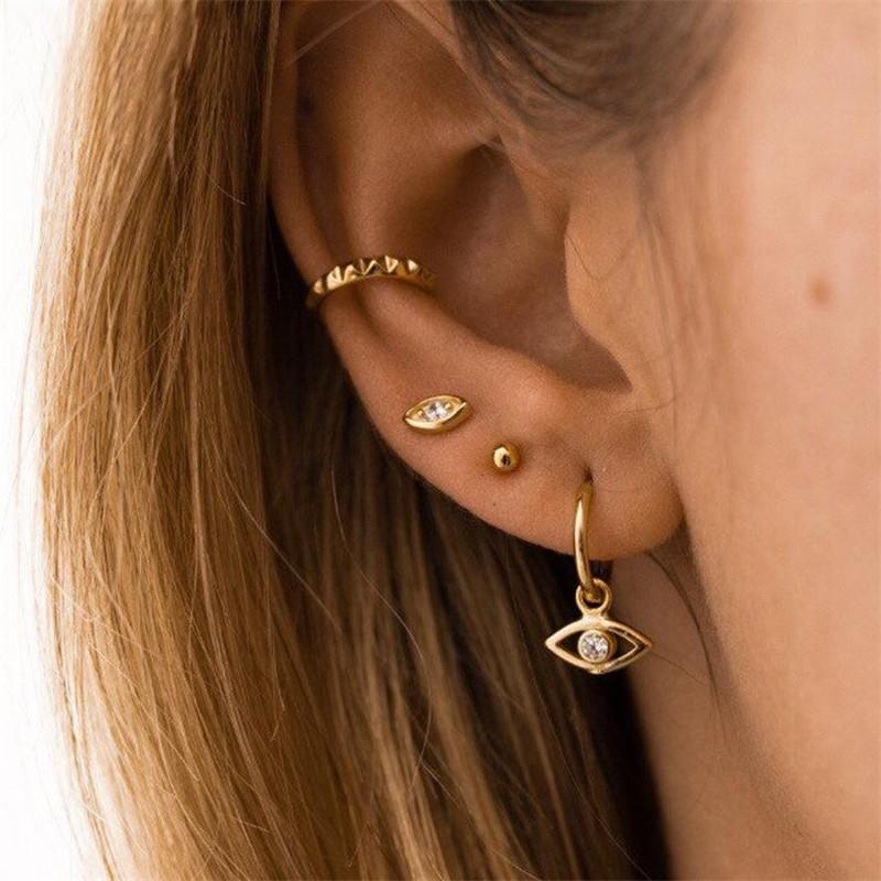 A model wearing multiple gold ear piercings.