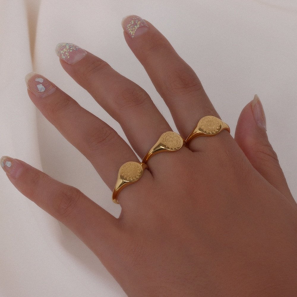 A model wearing three gold signet rings.