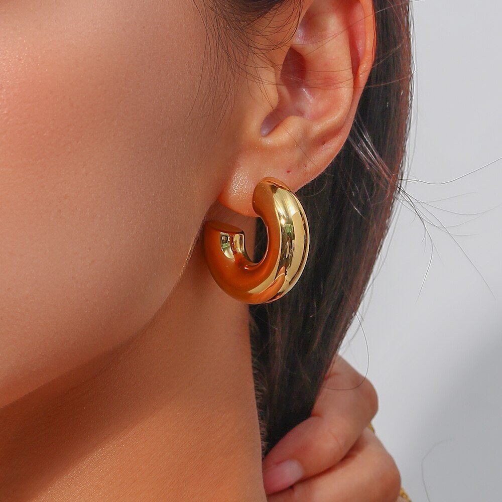 A model wearing gold Super Thick Hoop Earrings.