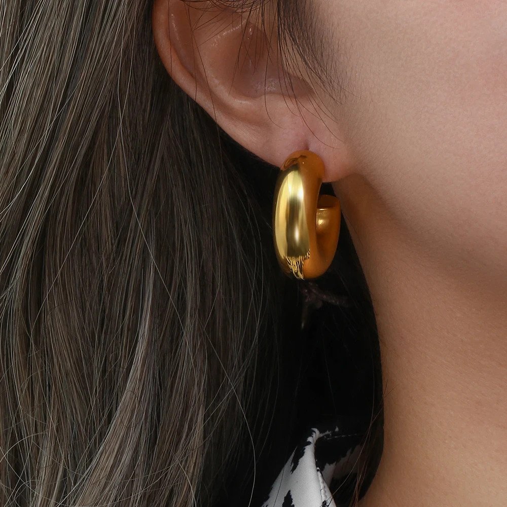 A woman wearing chunky gold hoops.