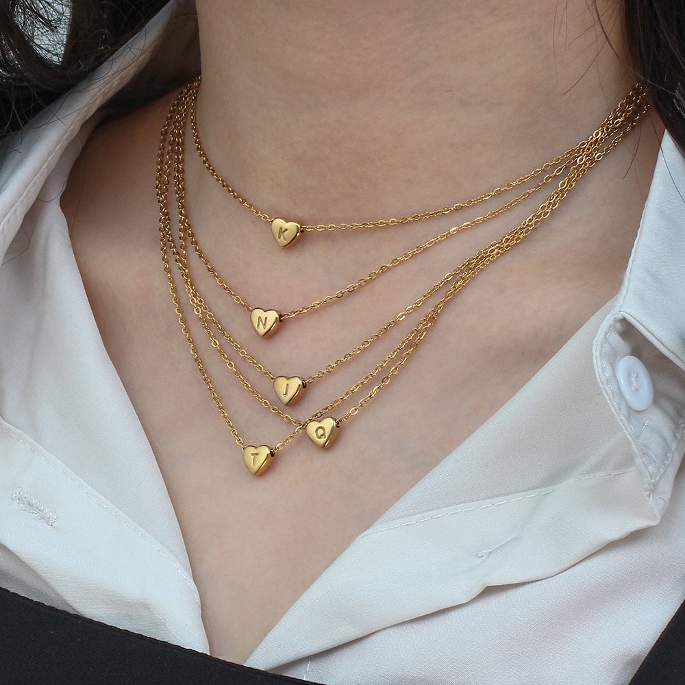 A model wearing a bunch of tiny gold heart necklaces.