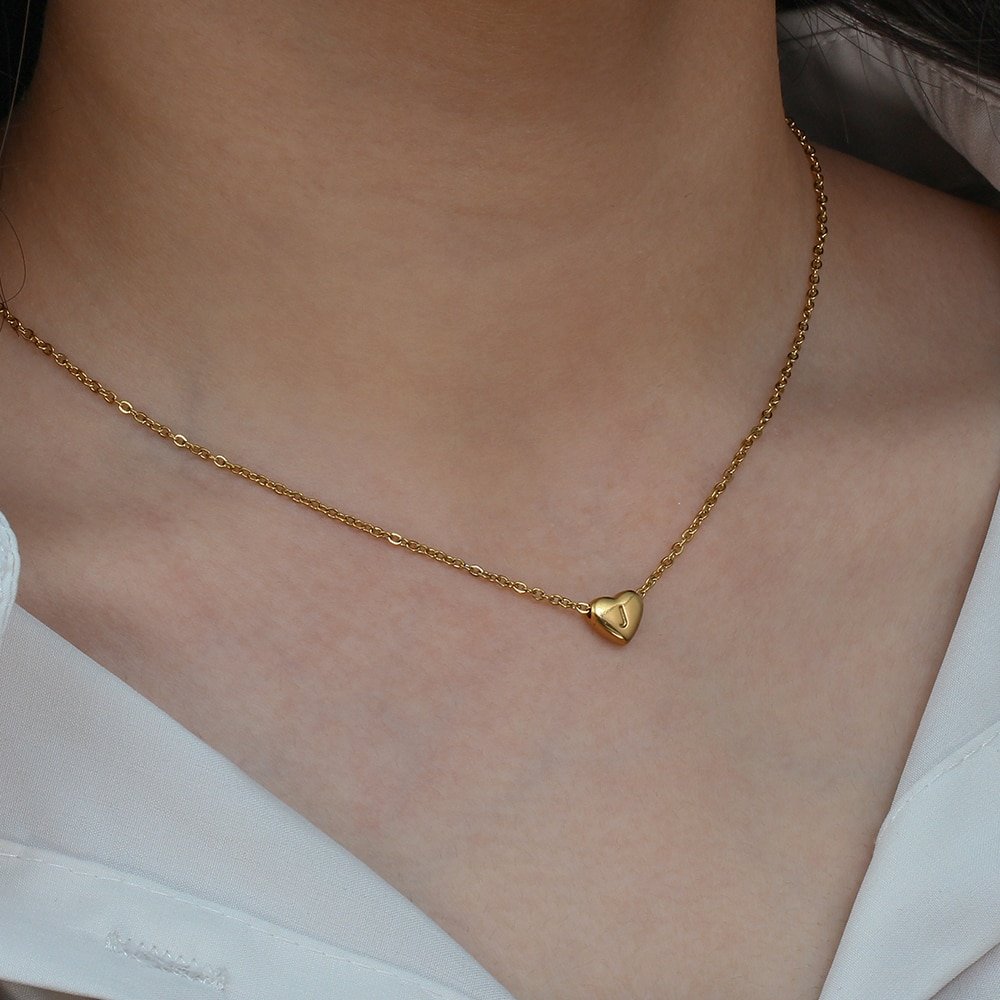 A model wearing a tiny gold heart necklace.