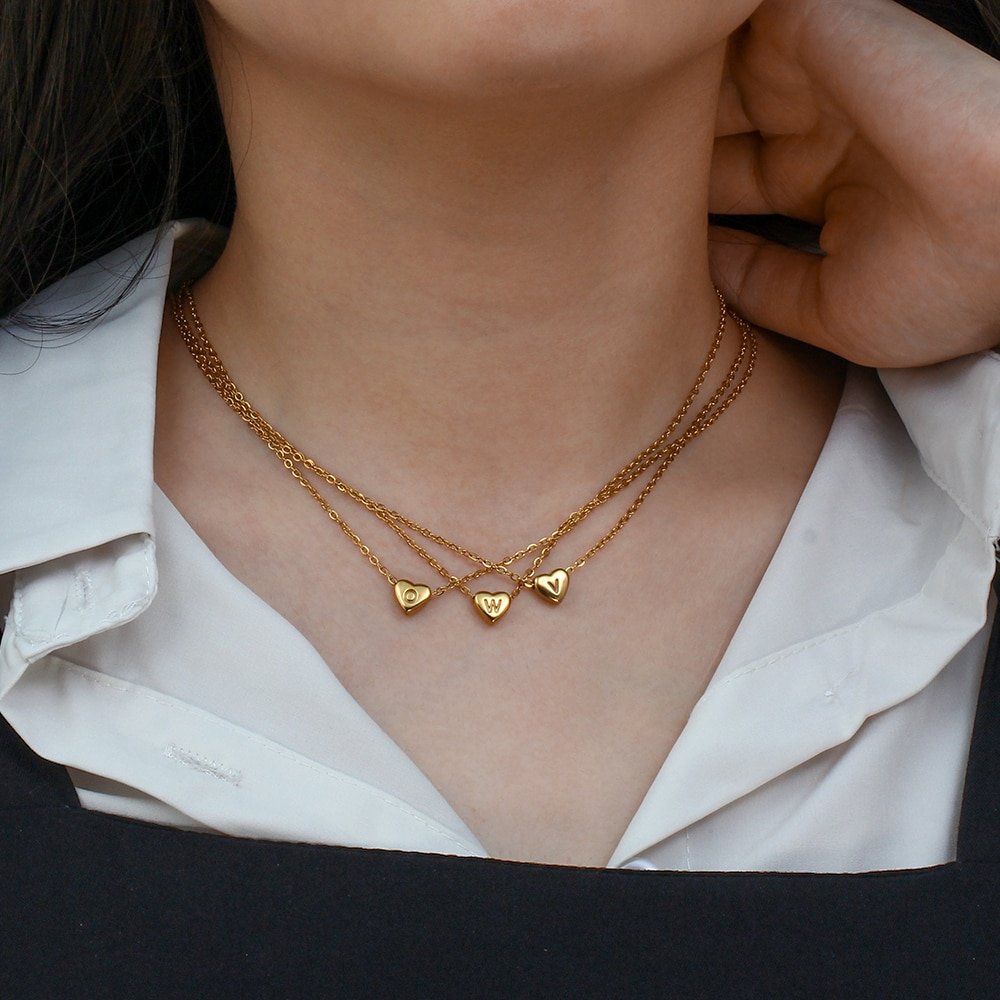 A woman wearing three Sweetheart Initial Necklaces.