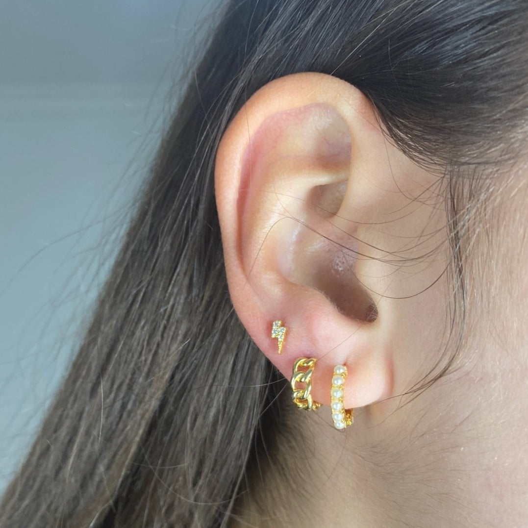 A model wearing gold lightning bolt earrings.